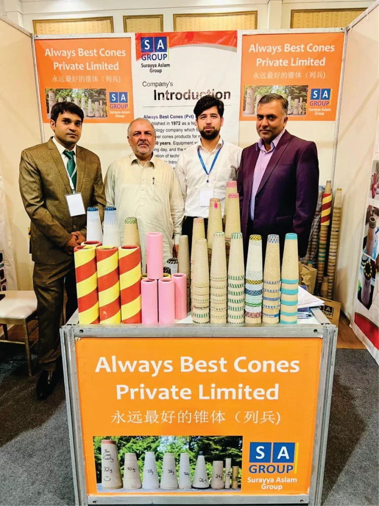 A group of four men standing together at the Always Best Cones booth, with various paper cones arranged on the table in front of them.
